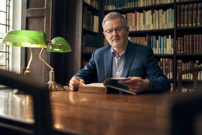 Frontansicht von Christopher Clark, ein Buch aufschlagend am Schreibtisch sitzend