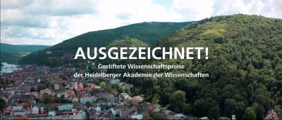 Titelbild des Ausgezeichnet-Film, Heidelberger Altstadt aus der Vogelperspektive, links die Stadt, rechts der Königstuhl. Im Vordergrund über dem Bild in weißer Schrift "AUSGEZEICHNET!" darunter kleiner "Gestiftete Wissenschaftspreise der Heidelberger Akademie der Wissenschaften"