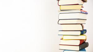 Stapel mit Büchern am linken Bildrand auf neutralem Hintergrund